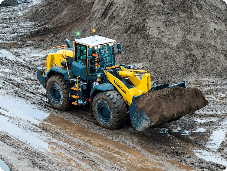 Ein LiuGong 890T der Erde über einen verregneten Platz transportiert.