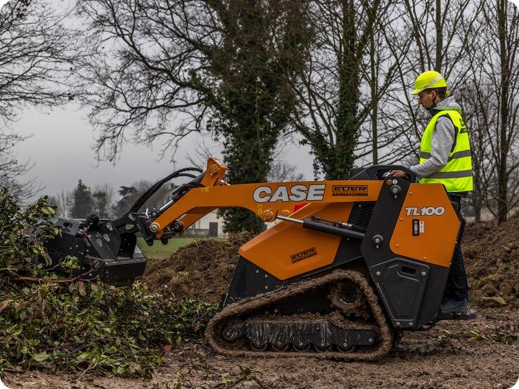 Case CE Mini-Raupenlader TL100 auf einer Baustelle mit einem Holzgreifer.